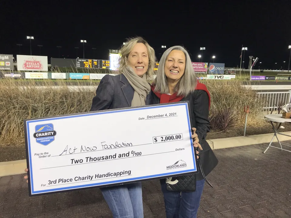 Act Now Foundation co-founders holding a large donation check at Meadowlands Racetrack fundraising event