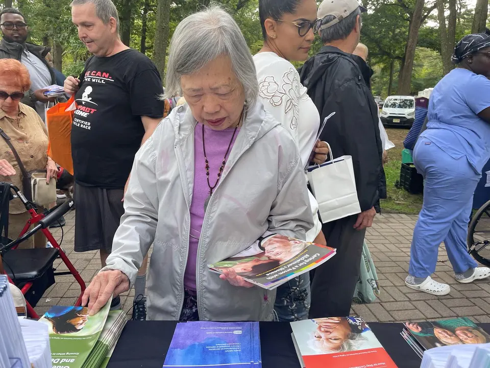 Persona mayor revisando recursos sobre demencia en un evento comunitario de Act Now Foundation en Nueva Jersey.