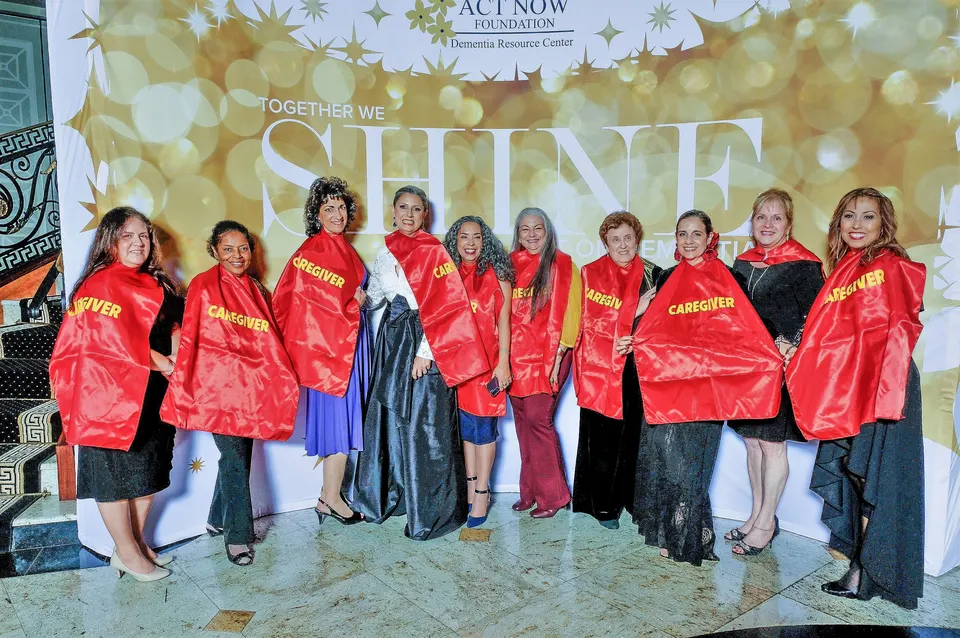 Grupo de cuidadores de Act Now Foundation con capas de superhéroe en un evento de gala