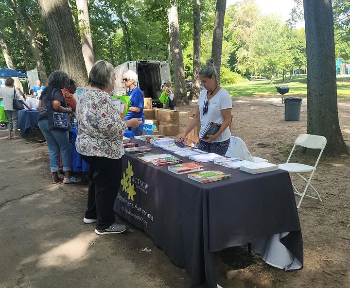 Personal de Act Now Foundation interactuando con familias en un stand educativo sobre demencia