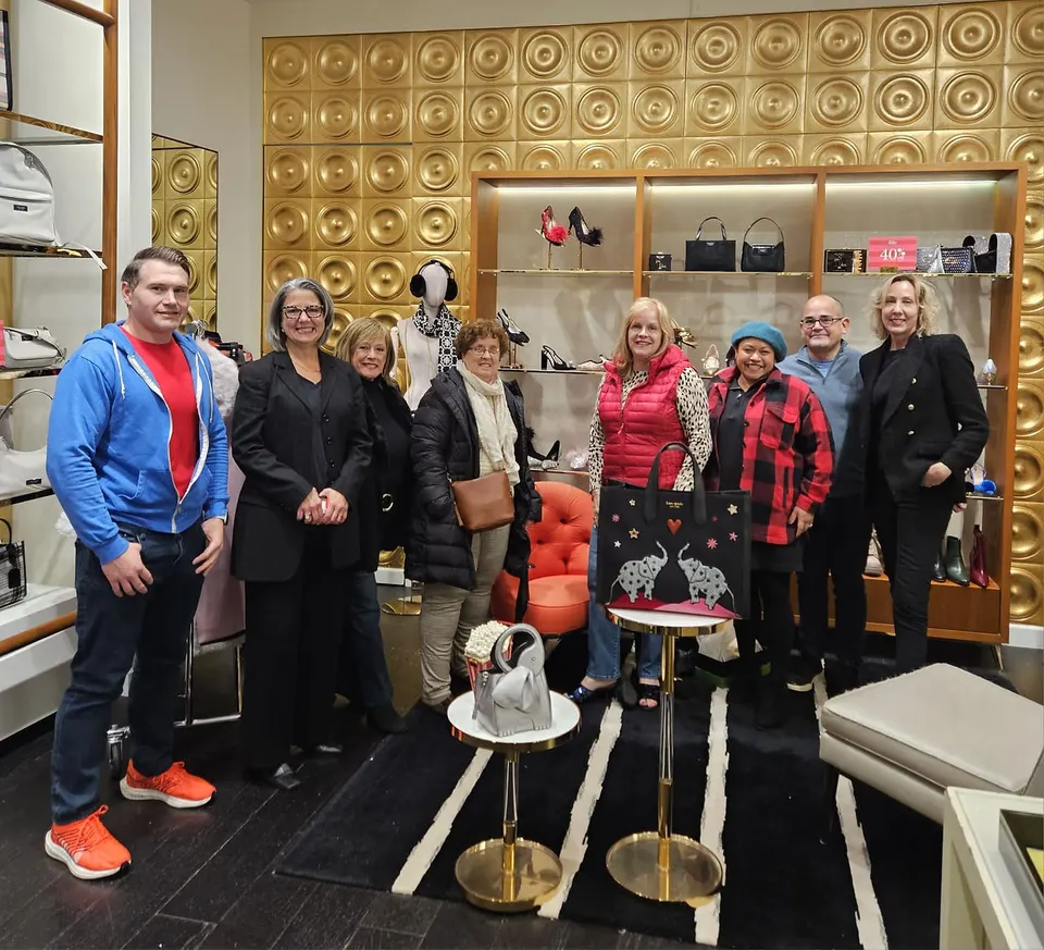Grupo de colaboradores y asistentes posando juntos en la venta benéfica de Kate Spade para Act Now Foundation