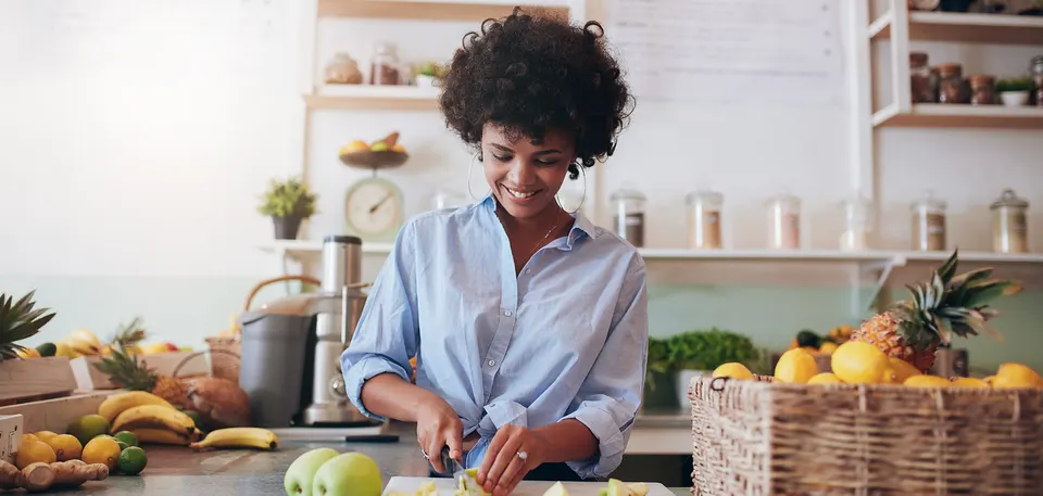 Mujer afroamericana joven preparando una comida saludable, que simboliza las decisiones de estilo de vida que pueden reducir el riesgo de Alzheimer