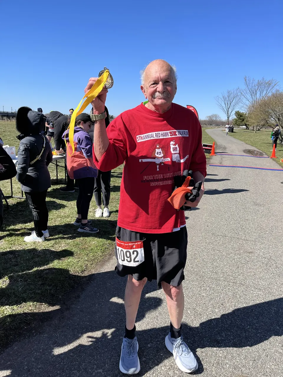 Senior participant holding a medal at a 5K walk and run supporting Act Now Foundation