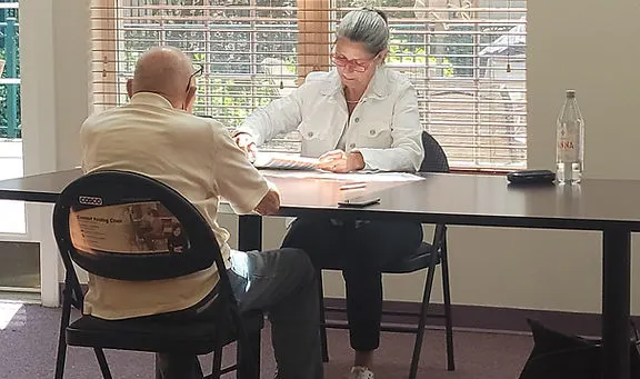 Profesional bilingüe especializado en demencia realizando una evaluación gratuita de memoria a una persona mayor en un evento comunitario.