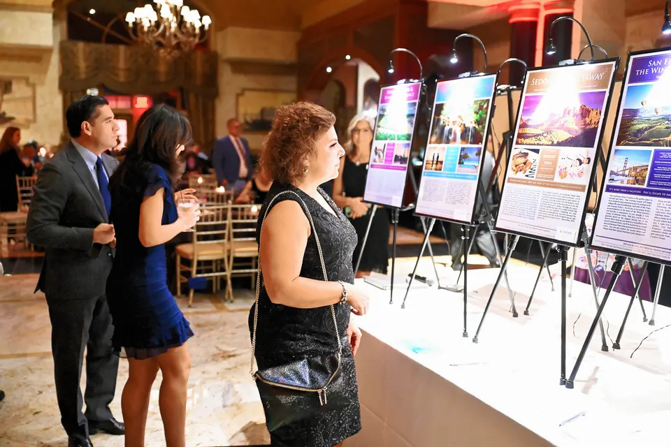 Asistente a la gala revisando artículos en la subasta silenciosa de viajes exclusivos