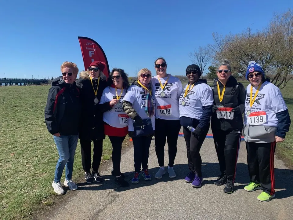 Grupo de participantes sonriendo y posando juntos en la línea de meta de la Carrera y Caminata 5K HardGrove