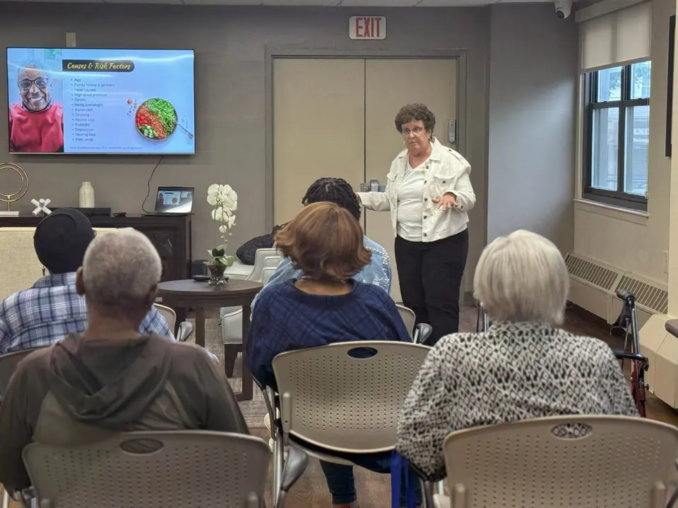 Educadora sobre demencia explicando las señales de alerta del Alzheimer durante un seminario